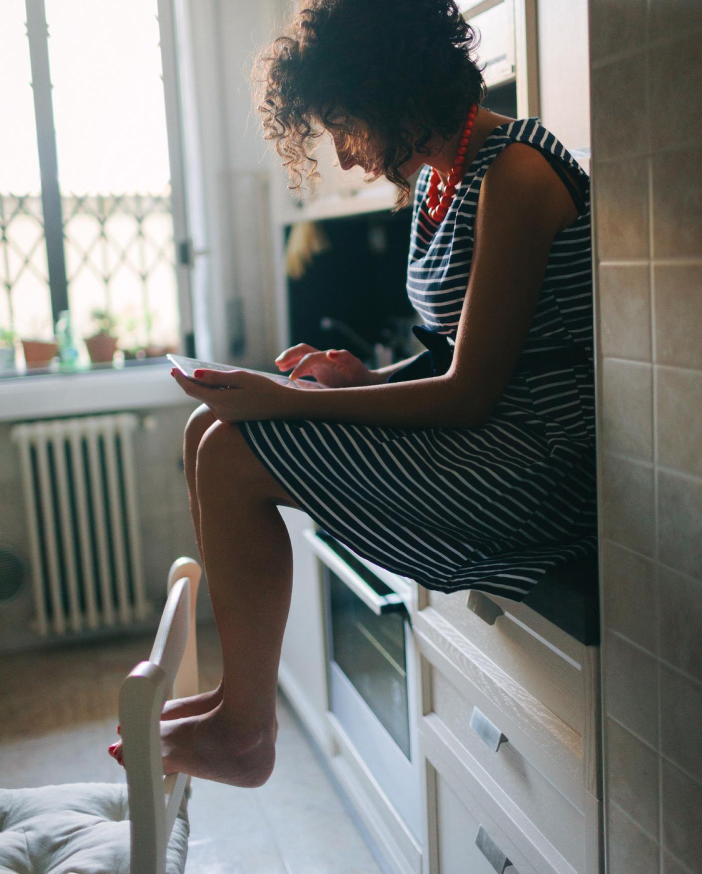 woman sitting on kitchen counter looking at ipad