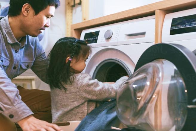 Little girl loading a washing machine